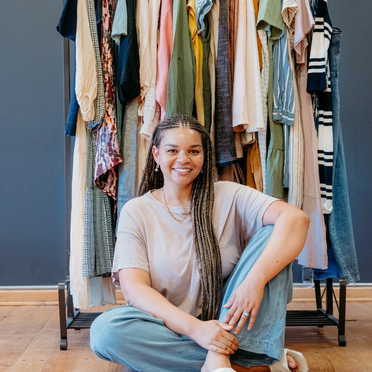Tish of The Reloved Boutique sitting in front of a rack of clothes.