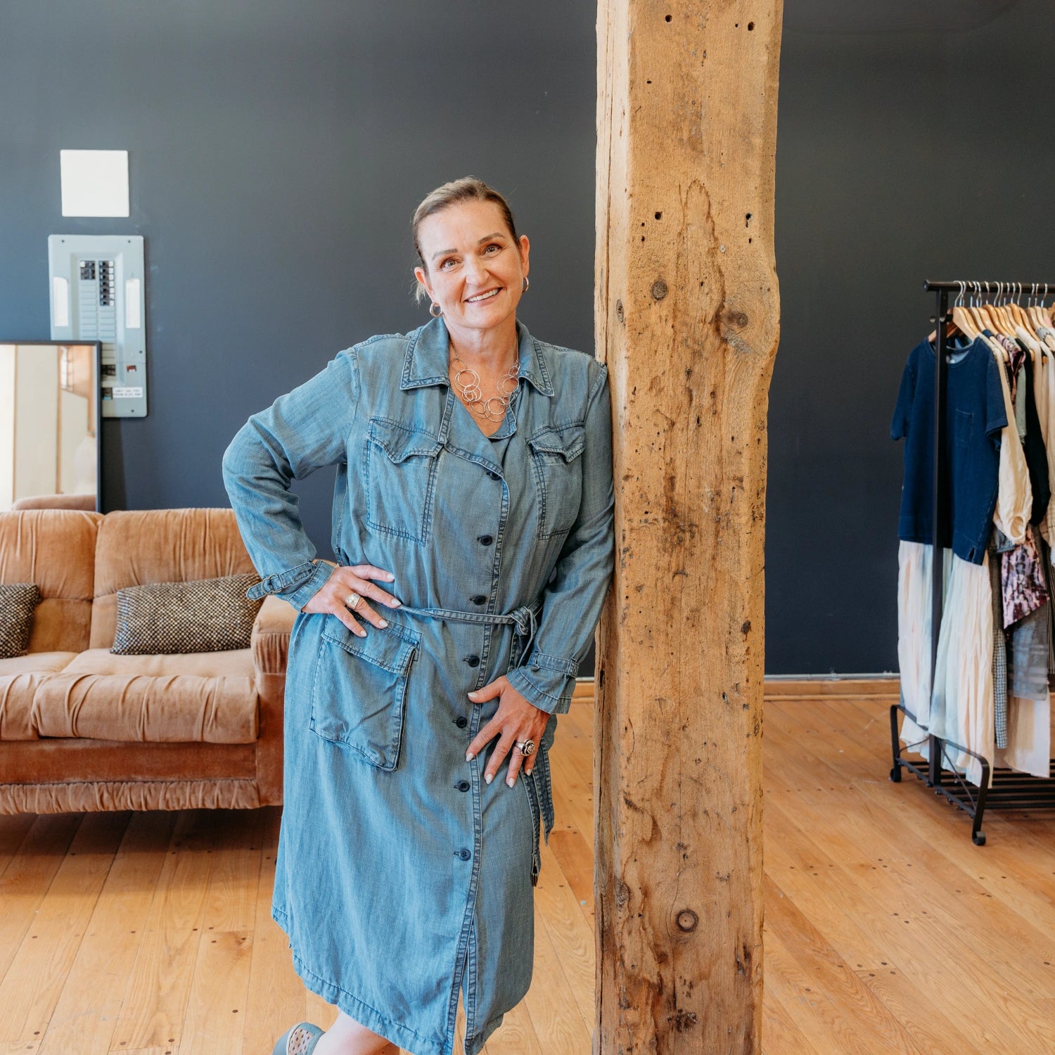 Raquel of The Reloved Boutique leaning against a wooden beam and smiling at the camera.
