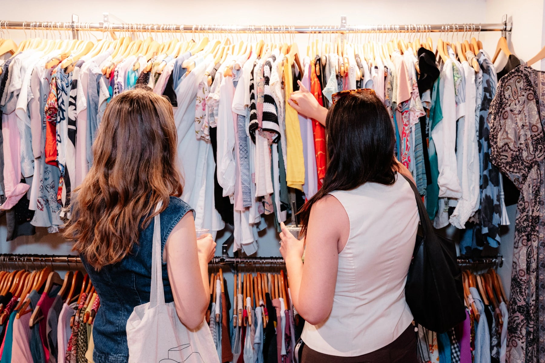 Two women shopping at The Reloved Boutique with racks of clothes.
