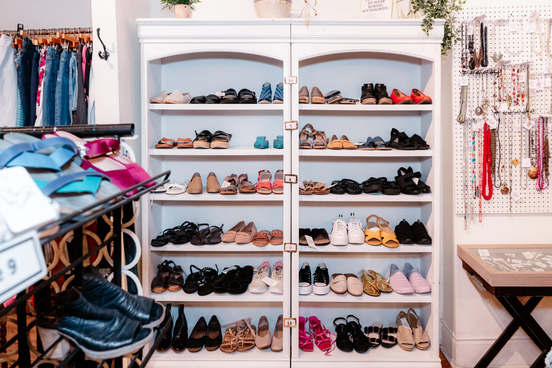 Shoe cabinet with various shoes displayed, surrounded by clothing and accessories at the Reloved Boutique.