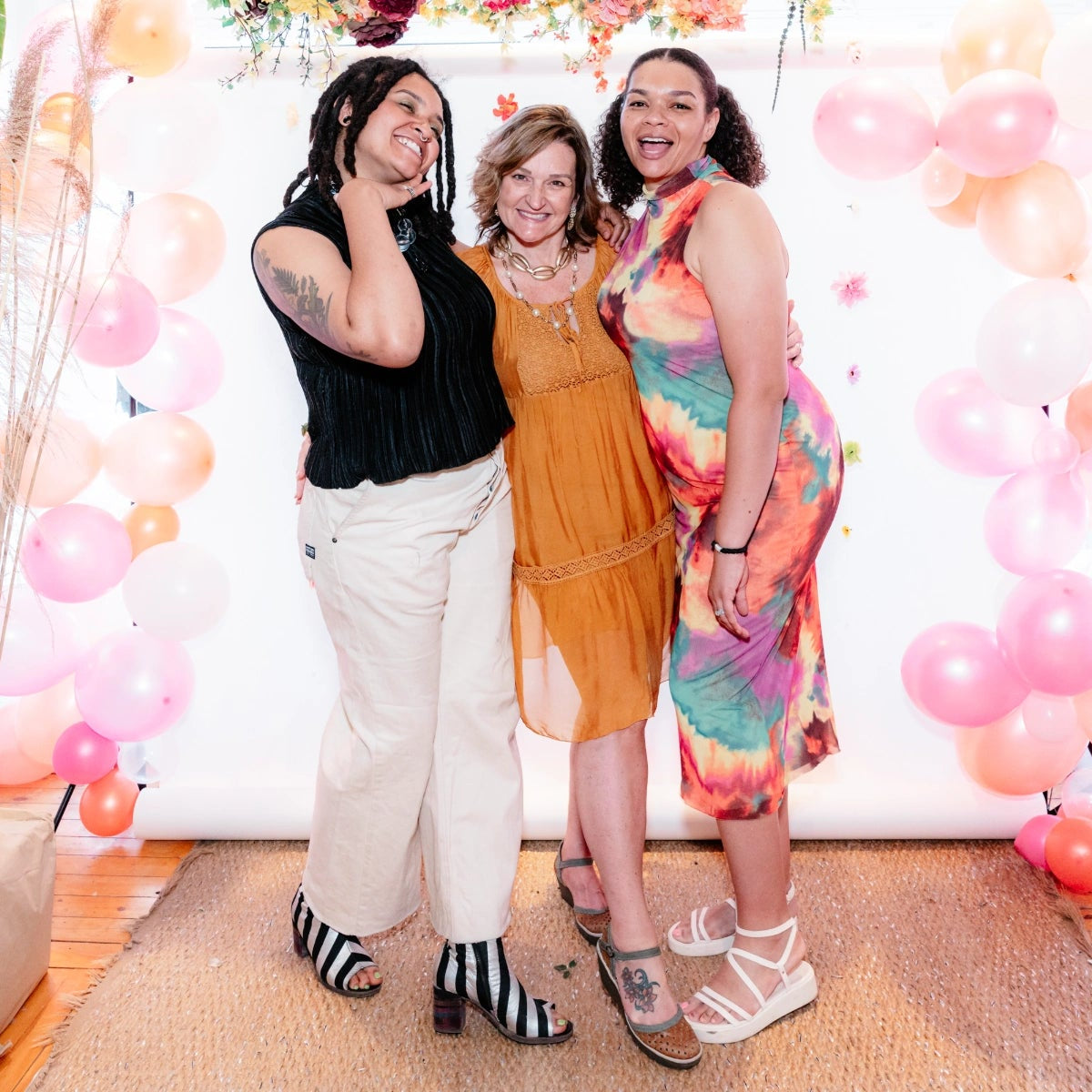 The Reloved Boutique owners posed together in a decorated room with balloons and plants.