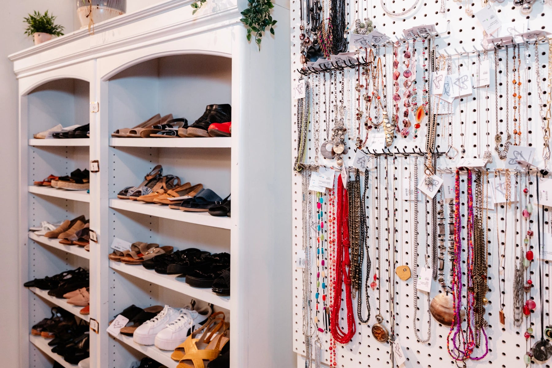 Shoe rack with various shoes and a pegboard with necklaces and jewelry.